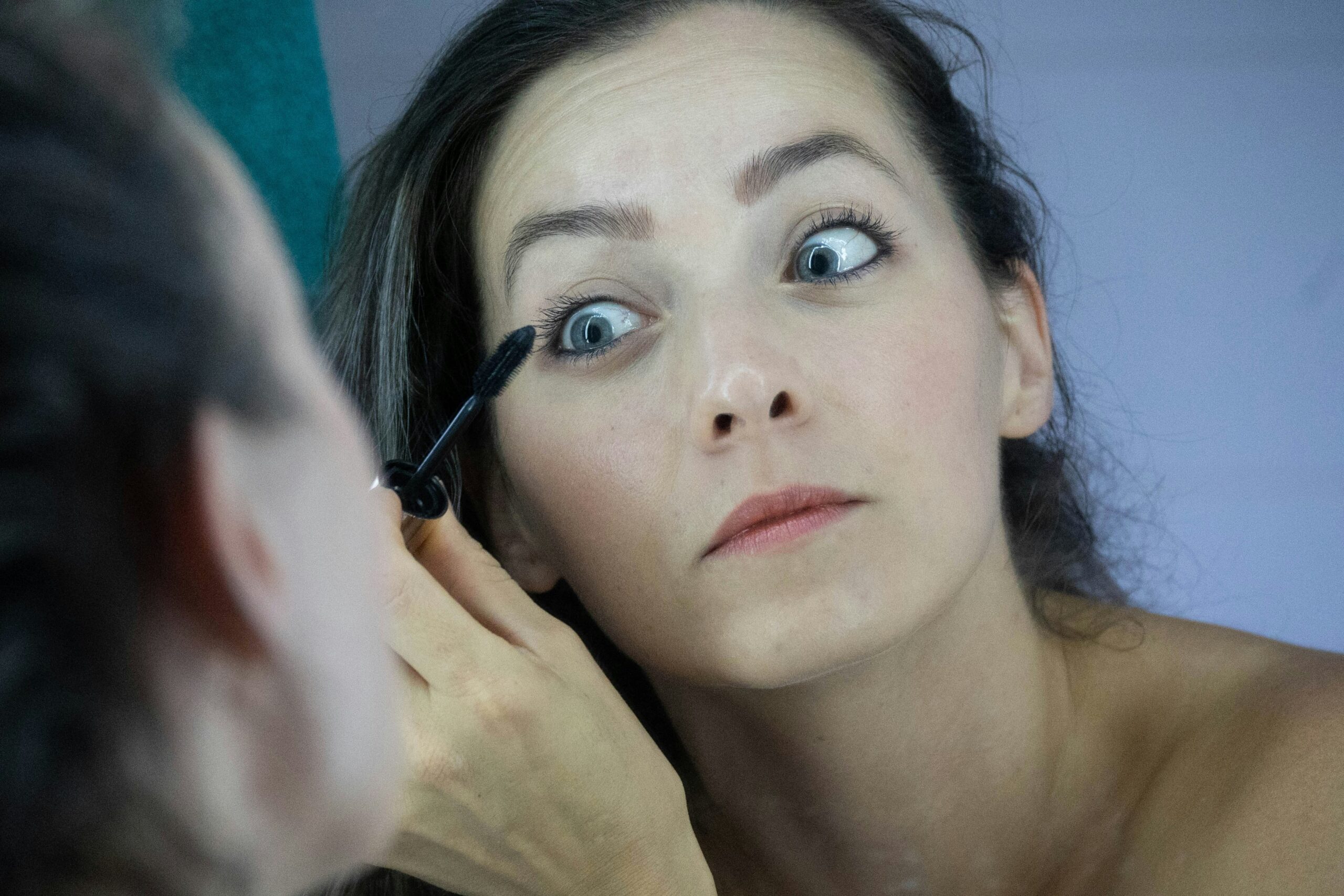 A close-up image showing an artist applying precise eyeliner on a model during editorial styling.