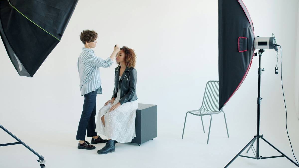 A professional makeup artist working on a model's face in a photography studio