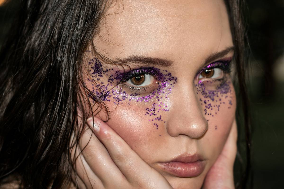 A woman holding a makeup brush, exasperated by her messy makeup attempt.
